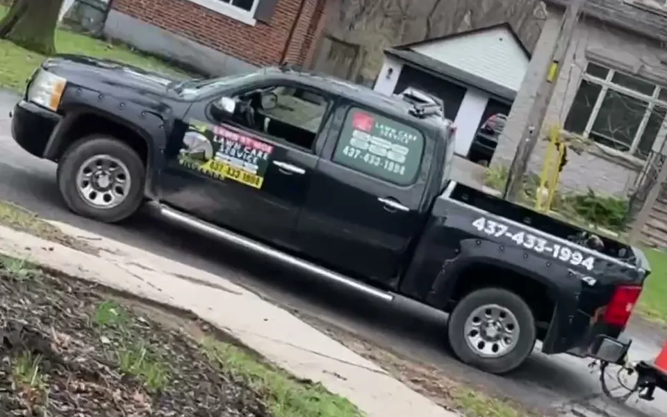 The Lawn By Moe truck with the phone number on the side, parked on a residential street