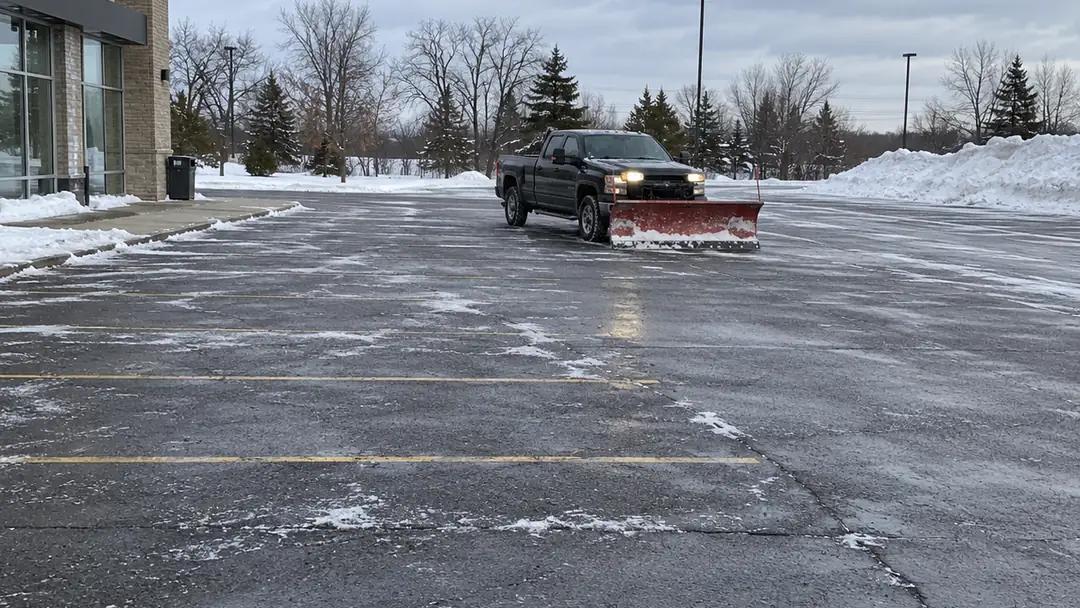 Pickup truck with a snow plow clearing a commercial parking lot, commercial snow removal in Milton